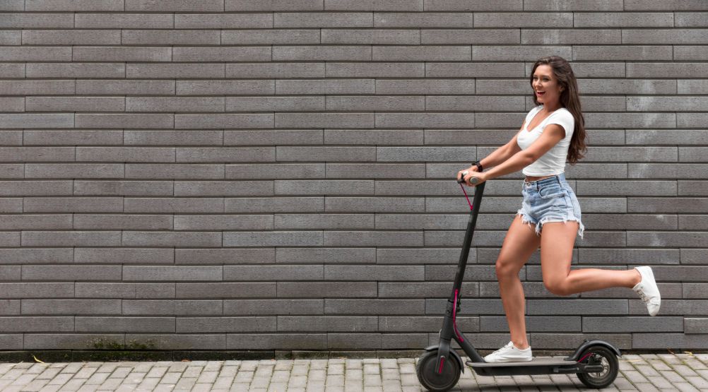 Happy woman riding an e-scooter for BoltChatAI's report on e-bikes and e-scooters